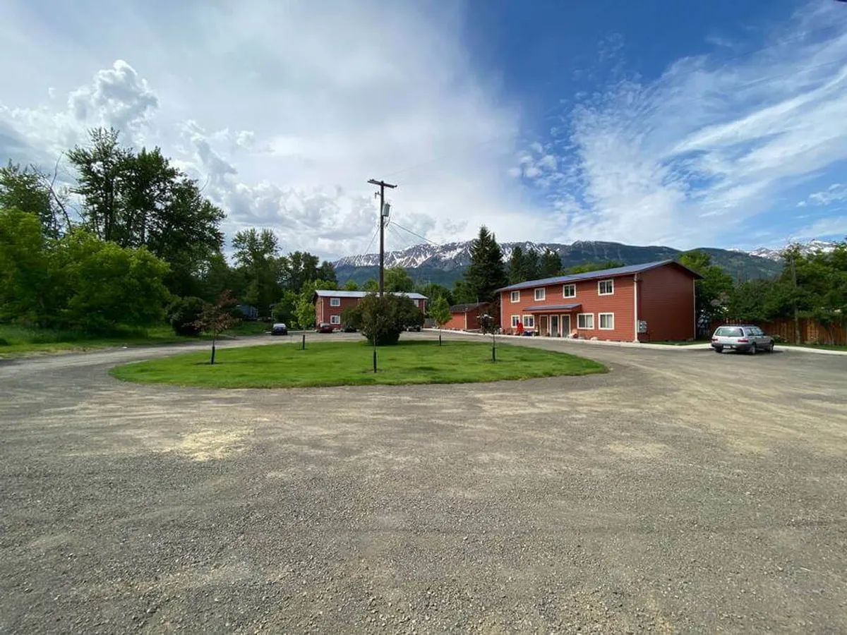 This image features the red exterior buildings of the property set against a stunning mountain backdrop. The landscaped green spaces and circular driveway hint at the close relationship between the property and its natural surroundings. The tranquil mood and open outdoor areas visually connect the home to the scenic environment.